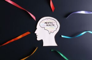 Cutout of Head on Black Background with Mental Health Text and Buzz Words in Brain