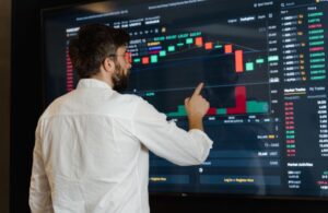 Male Data Analyst Looking at Data on Large TV Monitor