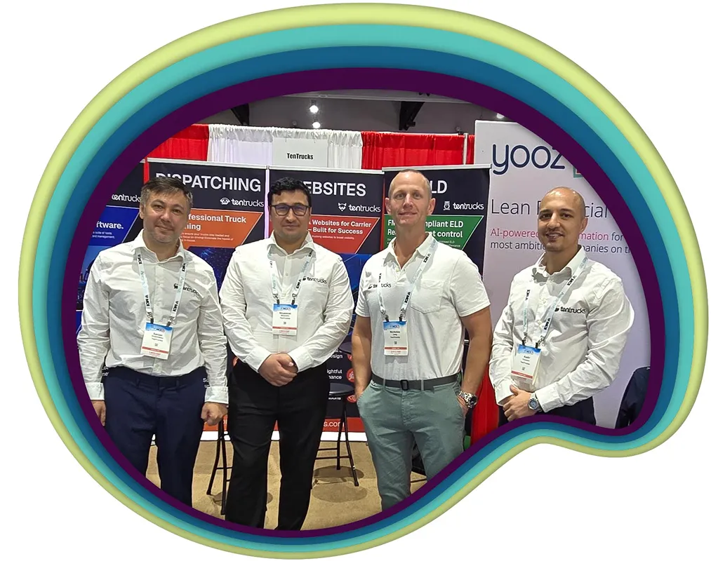 Four men in white shirts with company badges pose at a trade show booth featuring TenTrucks branding and promotional banners.