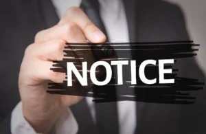 Person in business attire writing the word "NOTICE" in white over black marker strokes.