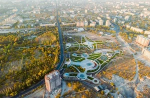 Aerial view of a city park with circular pathways and nearby residential buildings in autumn.