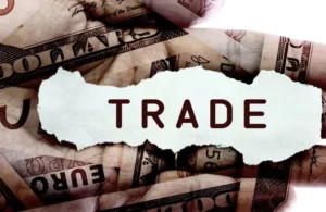 Close-up of overlapping US dollar and euro banknotes with torn paper displaying the word "TRADE" in bold letters.